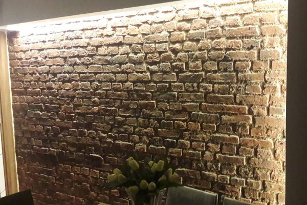 Heritage Faux Brick Wall Panel M267 A darkly lit living room with faux brick panels. The panels are lit with led strips for ambiance.