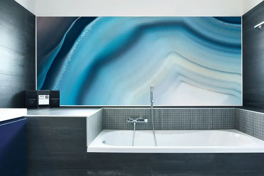 A peaceful spa-like bathroom has been created by using a panel of the blue Gargantua wall panel behind the bath.